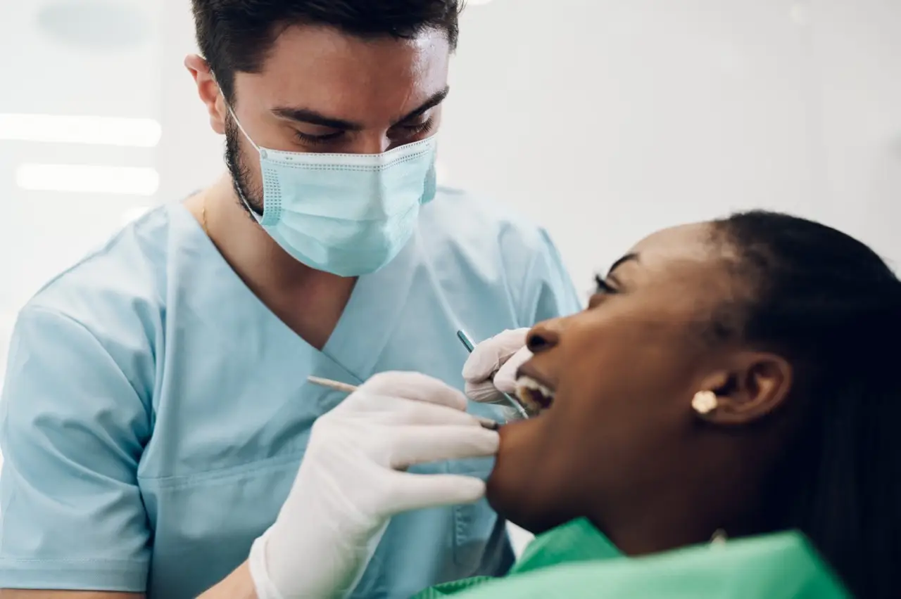 Dentist providing dental care treatment to a african american female patient
