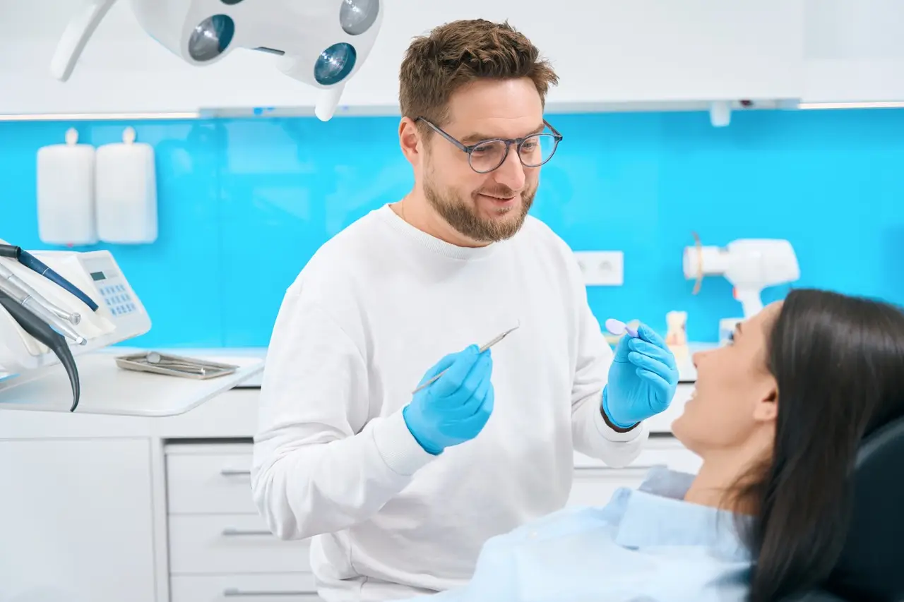 Friendly doctor stomatologist holding mouth mirror and sickle probe