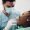 Young african american female patient with open mouth at dentist office. Black woman in dental clinic with male dentist fixing her teeth.