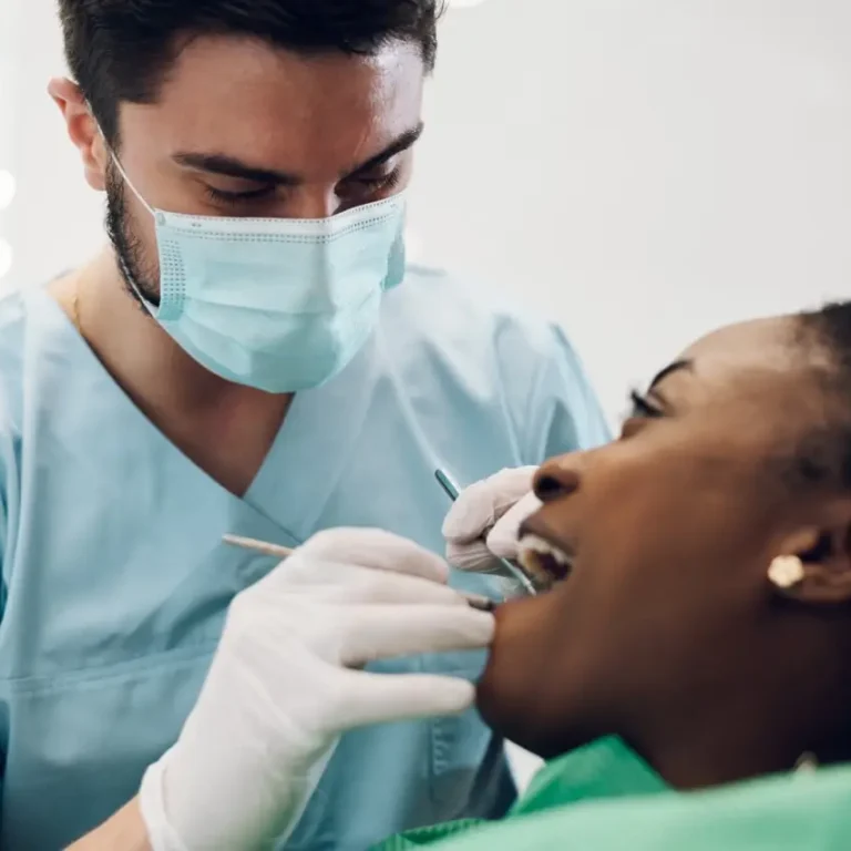 Dentist providing dental care treatment to a african american female patient
